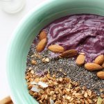 cherry and vanilla smoothie bowl topped with nuts, granola and seeds