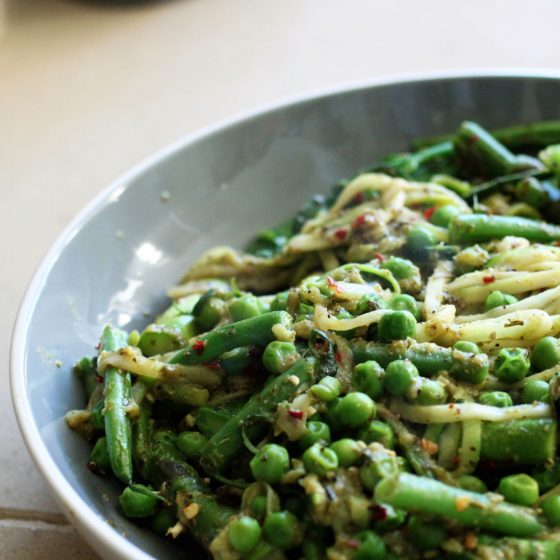 bowl of green vegetable courgetti against sandstone slab