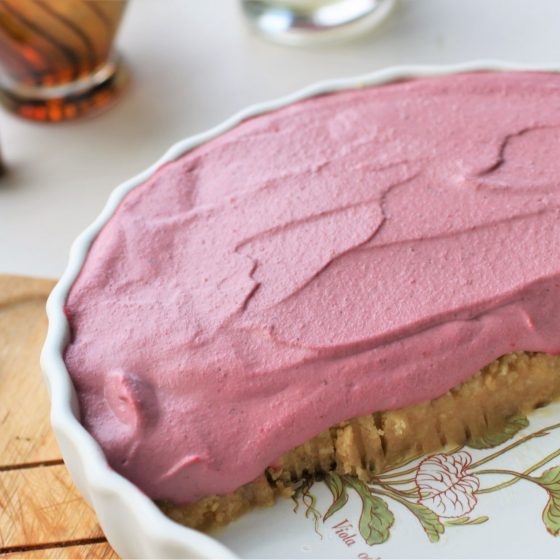 vegan strawberry cheesecake in a white dish, on a wooden tray