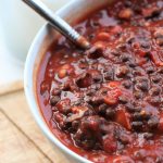 spicy lentil & bean bowl recipe in a while bowl on a wooden tray