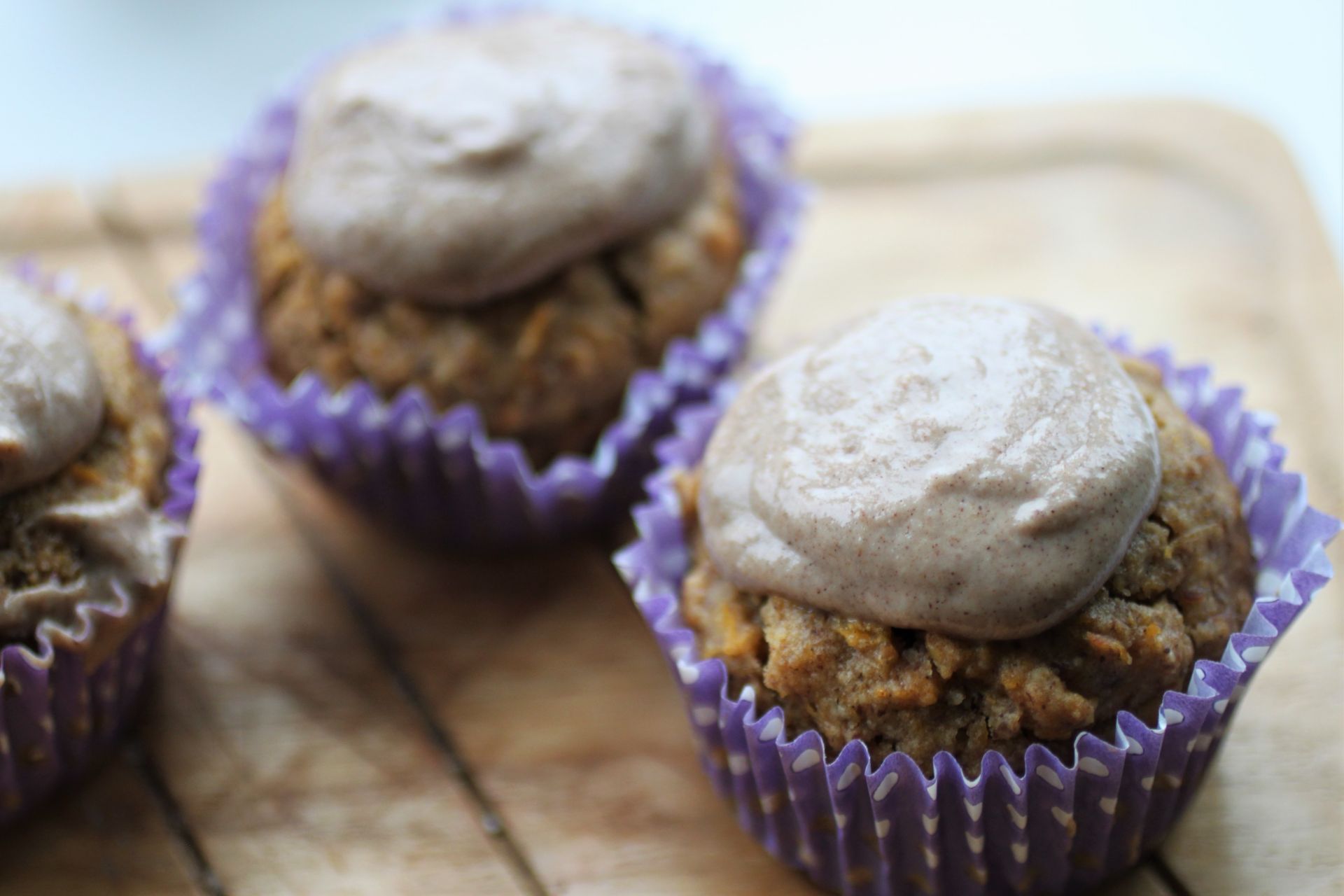 pumpkin cupcakes in purple and white spotty cases, with cashew cinnamon frosting on top