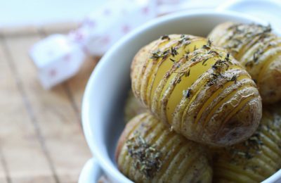 vegan hasselback potatoes in a white bowl, close up