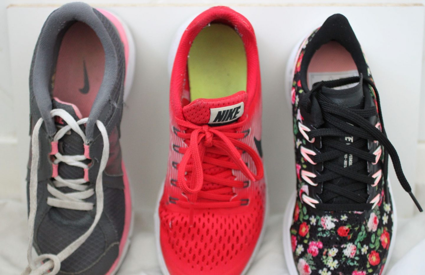 three running shoes lined up against a white wall