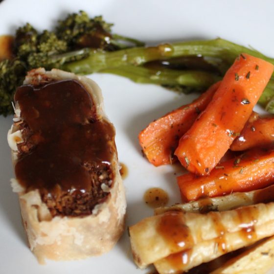 a square white plate with vegan wellington and some vegetables