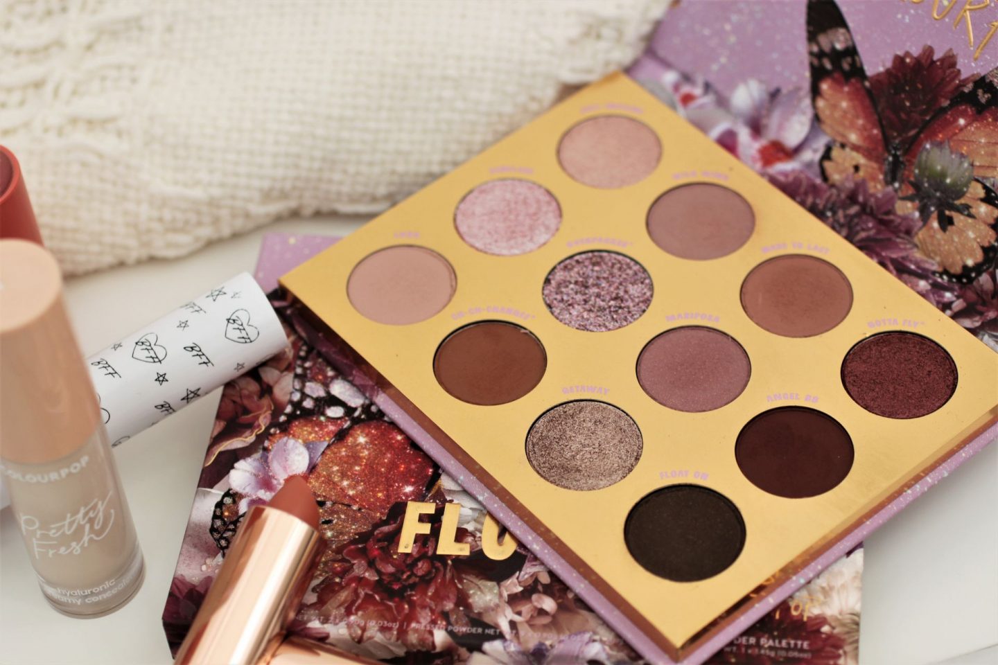 olourpop flutter by palette next to a nude lipstick on a white sheet
