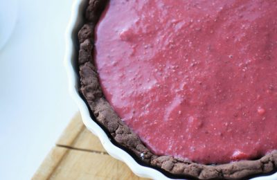Valentine's tart in a white pie dish on a wooden tray, against a white background