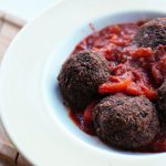 black bean meatballs in a bowl with a chili sauce on a wooden tray