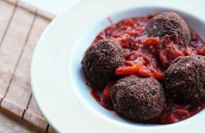 black bean meatballs in a bowl with a chili sauce on a wooden tray