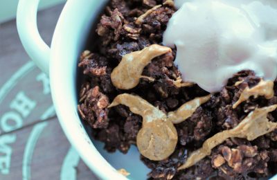 white bowl with brownie batter baked oats in, topped with yoghurt and peanut butter.