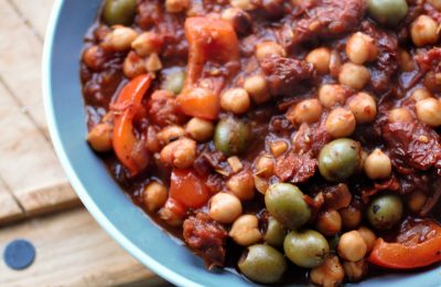grey pasta bowl with roasted pepper & chickpea casserole in, placed on a wooden board.