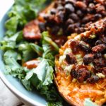 stuffed sweet potatoes in a large grey pasta bowl, placed on dark wooden boards