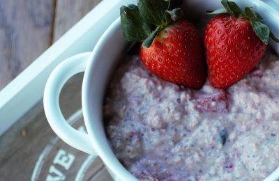 strawberry bircher muesli recipe in a white bowl with some fresh strawberries