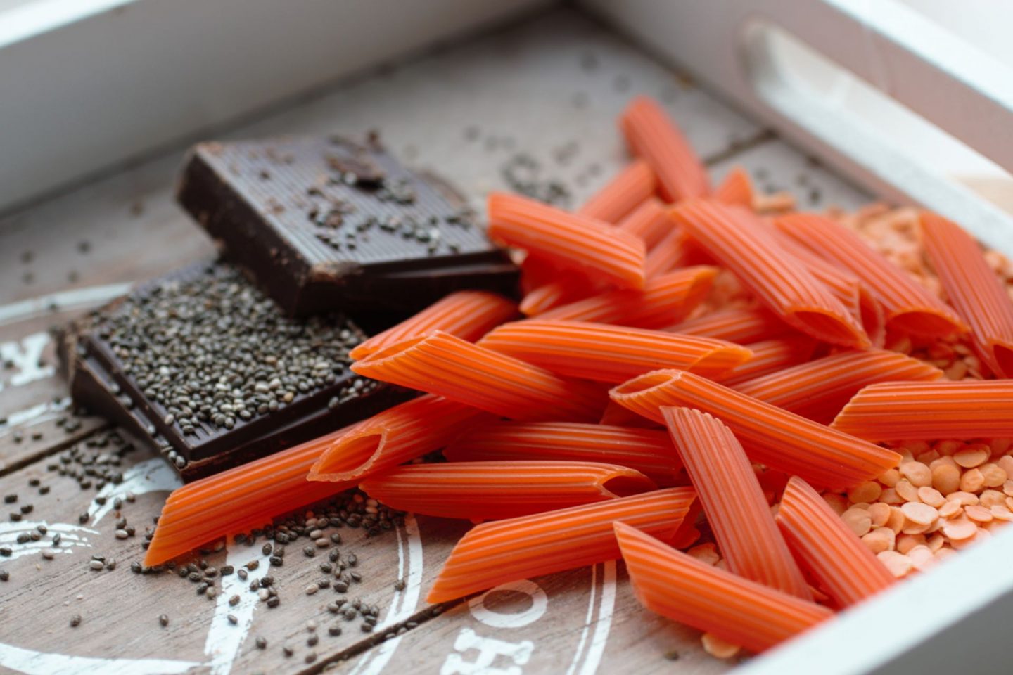 some high iron vegan foods on a tray - lentils, lentil pasta, dark chocolate and chia seeds