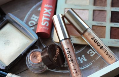 two bali body highlighter sticks on a wooden tray with other makeup