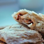 two italian bean pasties on a wooden board, one cut open to show inside