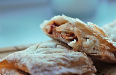 two italian bean pasties on a wooden board, one cut open to show inside