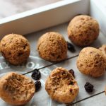 grey wooden tray with carrot cake energy balls on it, and raisins sprinkled over the tray