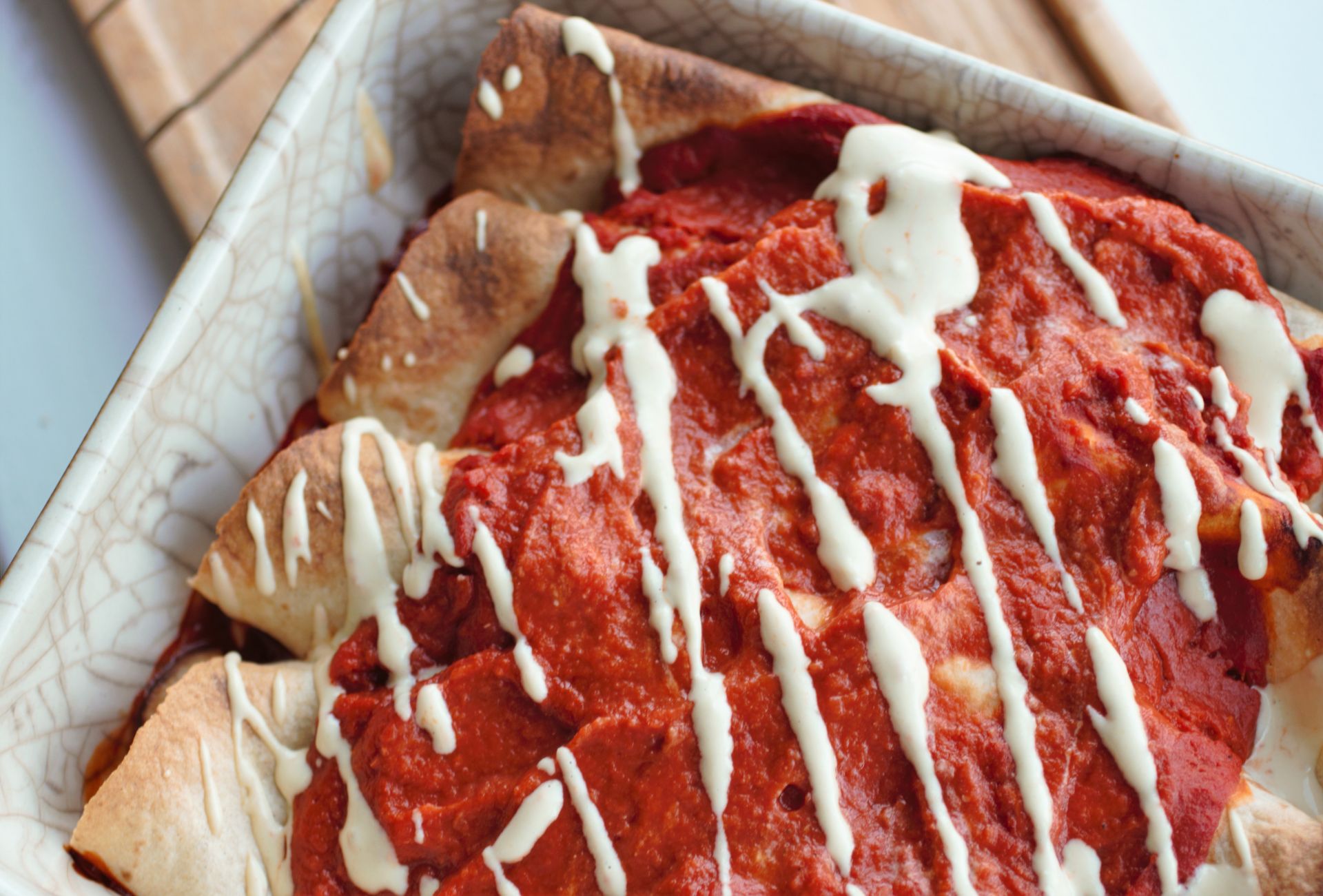 batch of cooked lentil enchiladas in a dish, placed on a wooden board