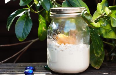 creamy overnight tropical breakfast jar on a wooden bench with some leaves behind it