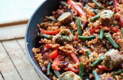 vegan paella recipe in pan, placed on wooden board