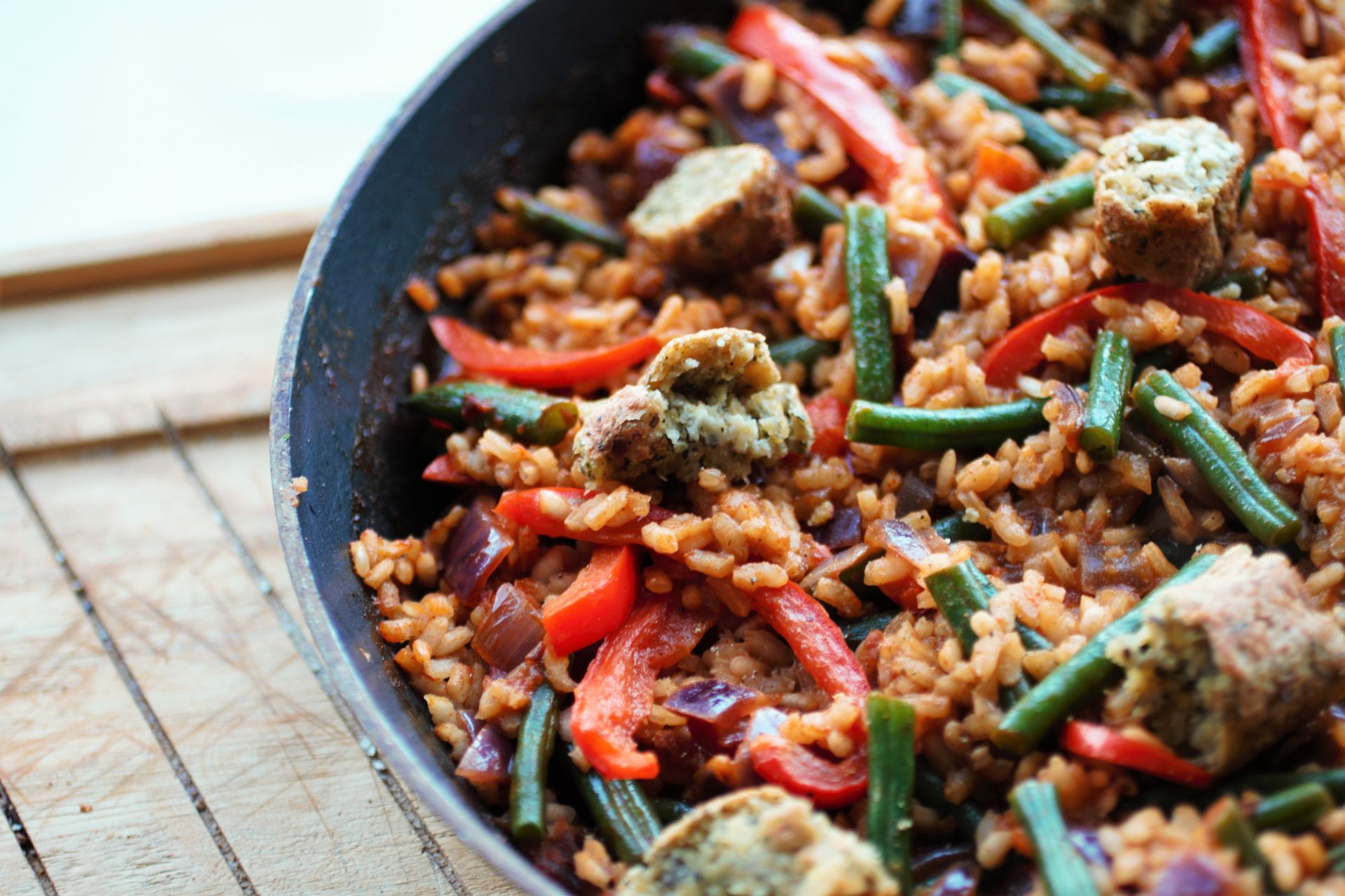 vegan paella recipe in pan, placed on wooden board