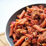 vegan sausage pasta recipe in a large pasta bowl placed on a wooden tray