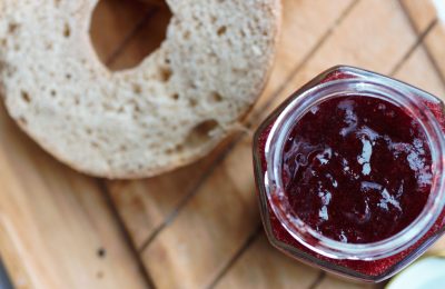 pot of strawberry jam and a sliced bagel, birds eye view