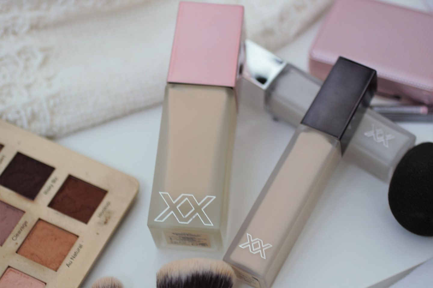 xx revolution foundation and concealer on a white board with other makeup