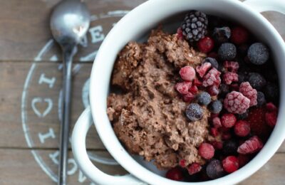 white bowl on a grey wooden tray, filled with chocolate overnight oats and berries
