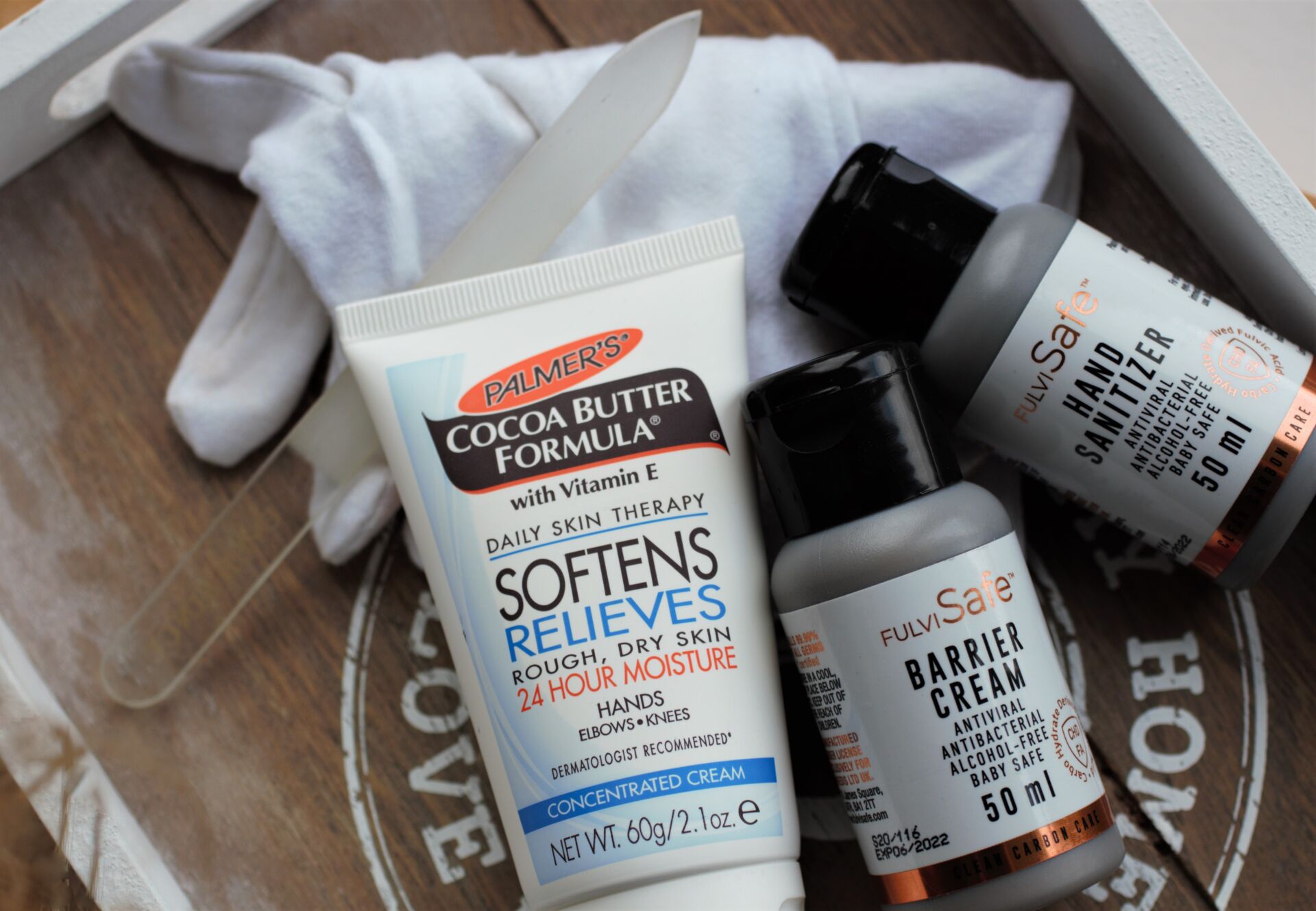 Palmers hand cream and anti viral hand products on a wooden board with some moisturising gloves