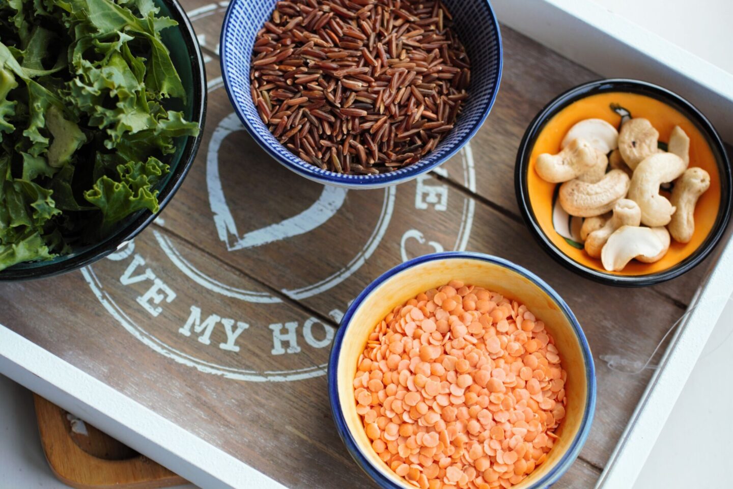 a wooden board with lots of small dishes on, each containing grains/ nuts that are plant based zinc sources