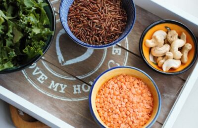 a wooden board with lots of small dishes on, each containing grains/ nuts that are plant based zinc sources