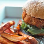 all veggie burger and sweet potato fries on a wooden board
