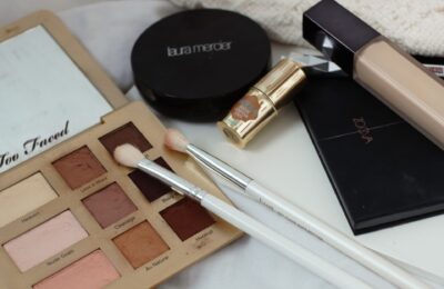 everyday minimal makeup products on a white wooden board and white sheet