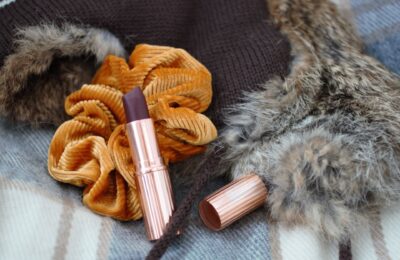 autumnal accessories - a scarf and fluffy hat with a berry toned lipstick on top