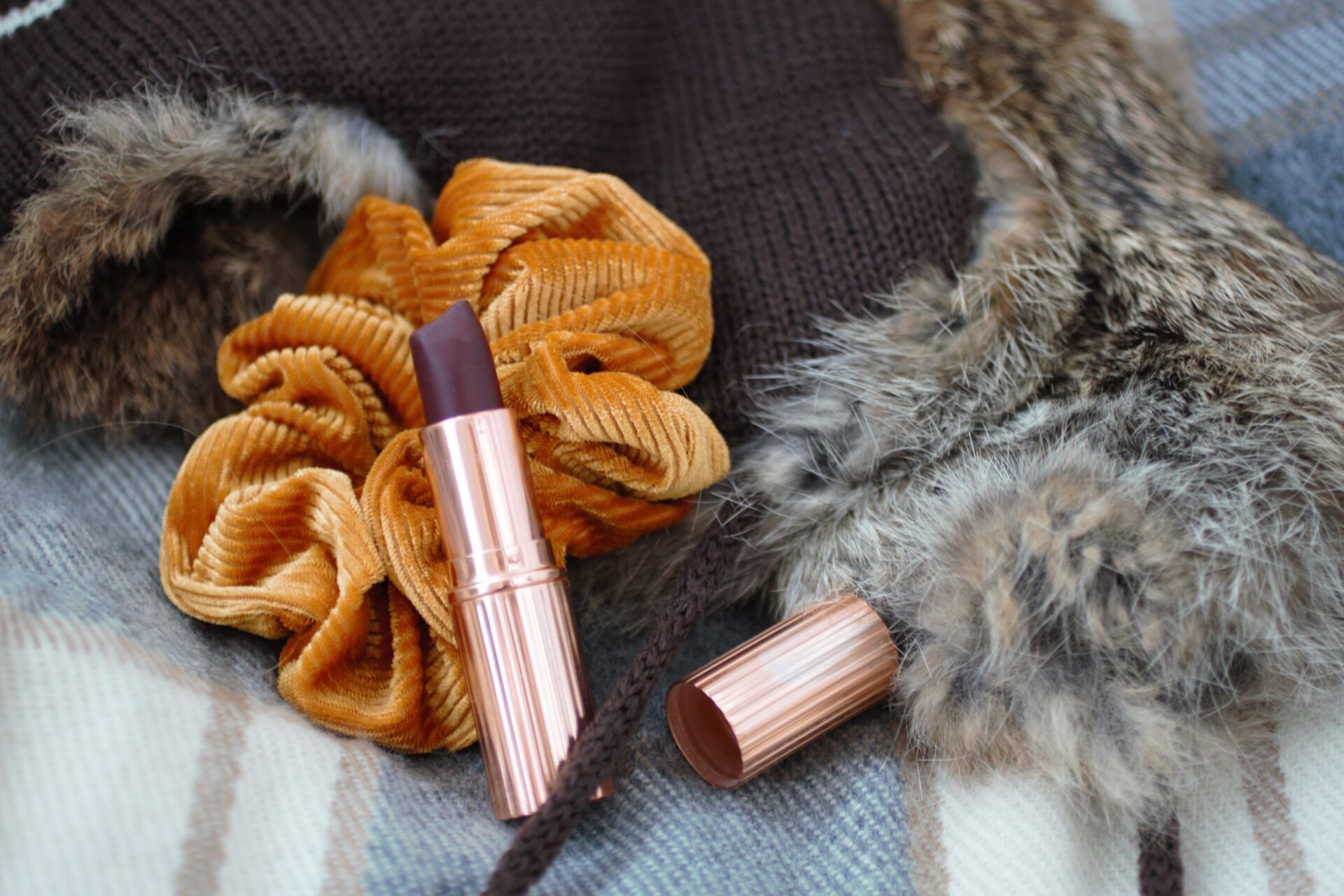 autumnal accessories - a scarf and fluffy hat with a berry toned lipstick on top