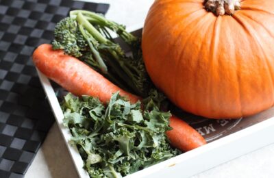 a tray with a pumpkin, kle and some other plant based sources of vitamin A on it