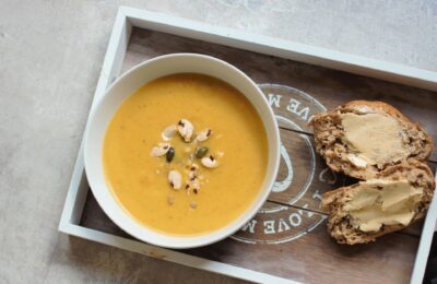 bowl of pumpkin soup on a grey tray with bread