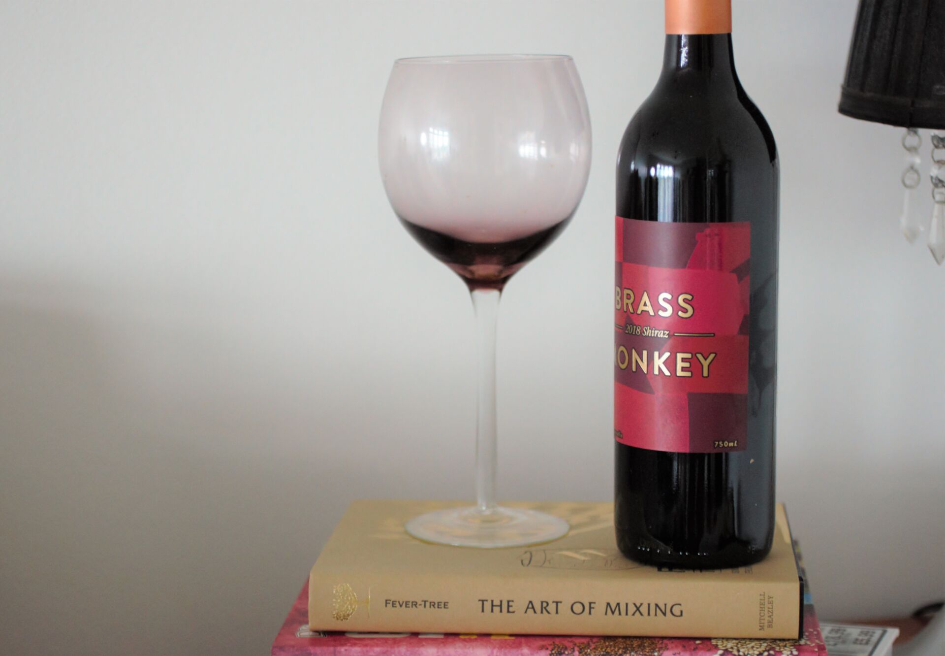 wine bottle and glass placed on op of a cocktails recipe book