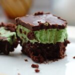 vegan mint three layer brownie on a plate with a fork next to it