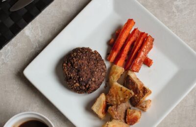 shiitake nut patty on a white plate with some of the other dinner ingredients