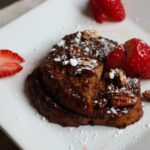 chocolate French toast on a square white plate with toppings