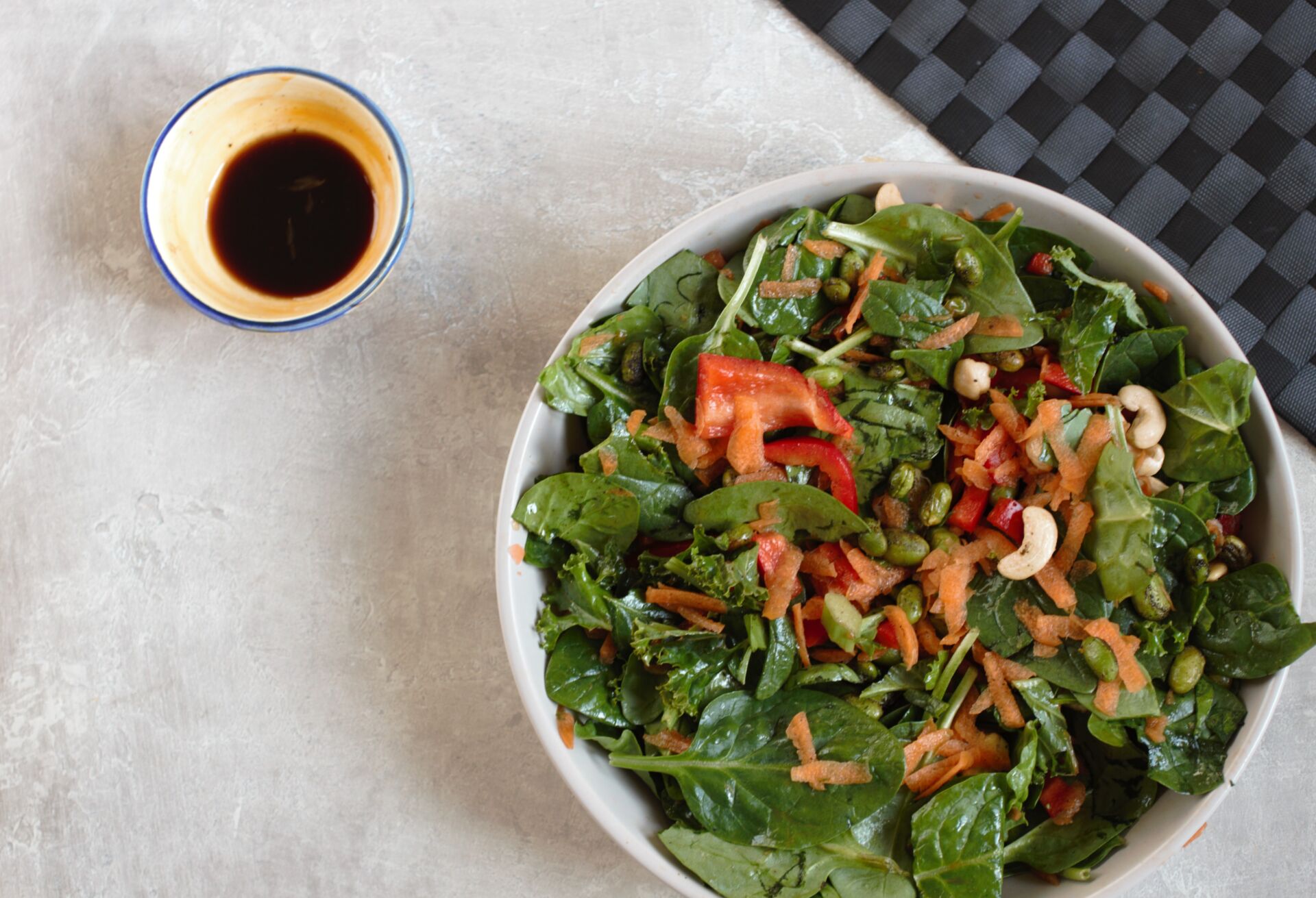 orange edamame salad recipe in a large bowl with a pot of dressing beside it