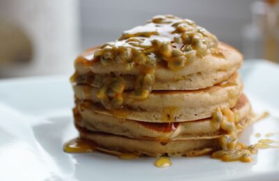 stack of mango and passionfruit pancakes on a white plate