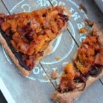 vegan caramelised squash pizza tarts sliced on a grey wooden tray