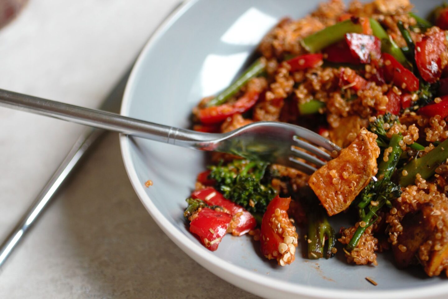 bowl of tomato quinoa with a fork in it