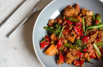 bowl of easy tomato quinoa recipe in a grey pasta bowl with a knife and fork to the side