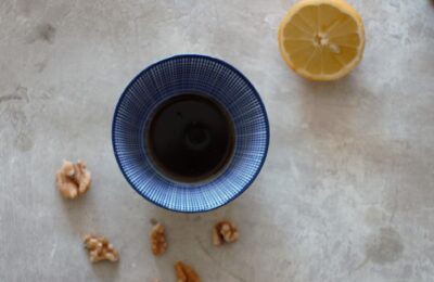 small pot of walnut oil balsamic vinaigrette recipe with some walnuts and half a lemon placed around it