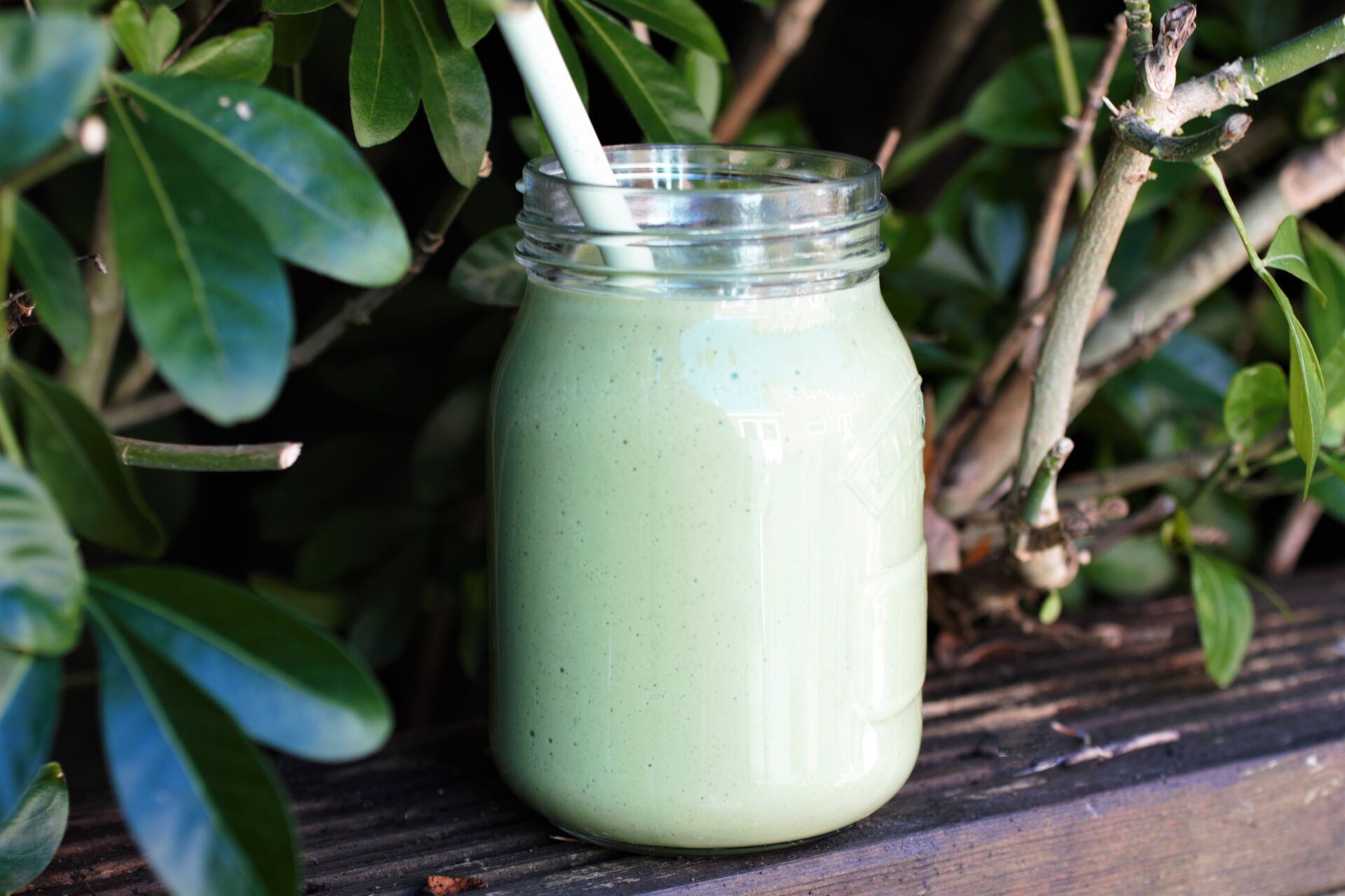 green smoothie recipe in a glass jar, outside next to some plants