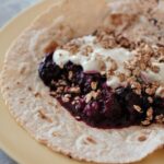 breakfast tortilla recipe on a plate, topped with vegan yoghurt and berry compote, shot from the side
